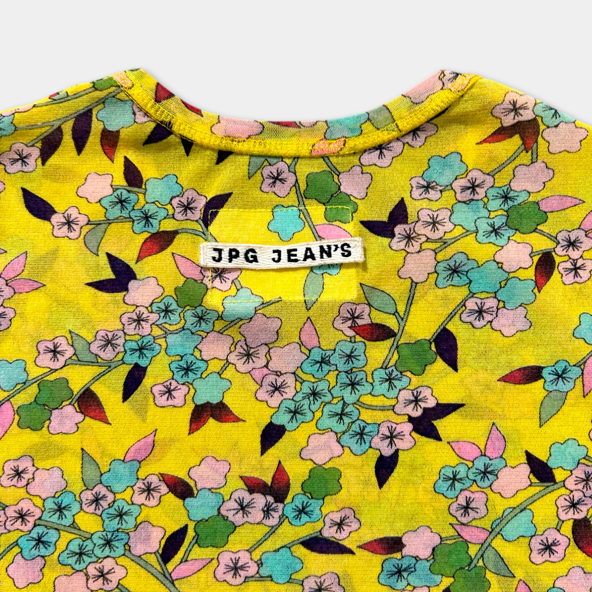 a yellow floral print shirt with a white label on the collar.