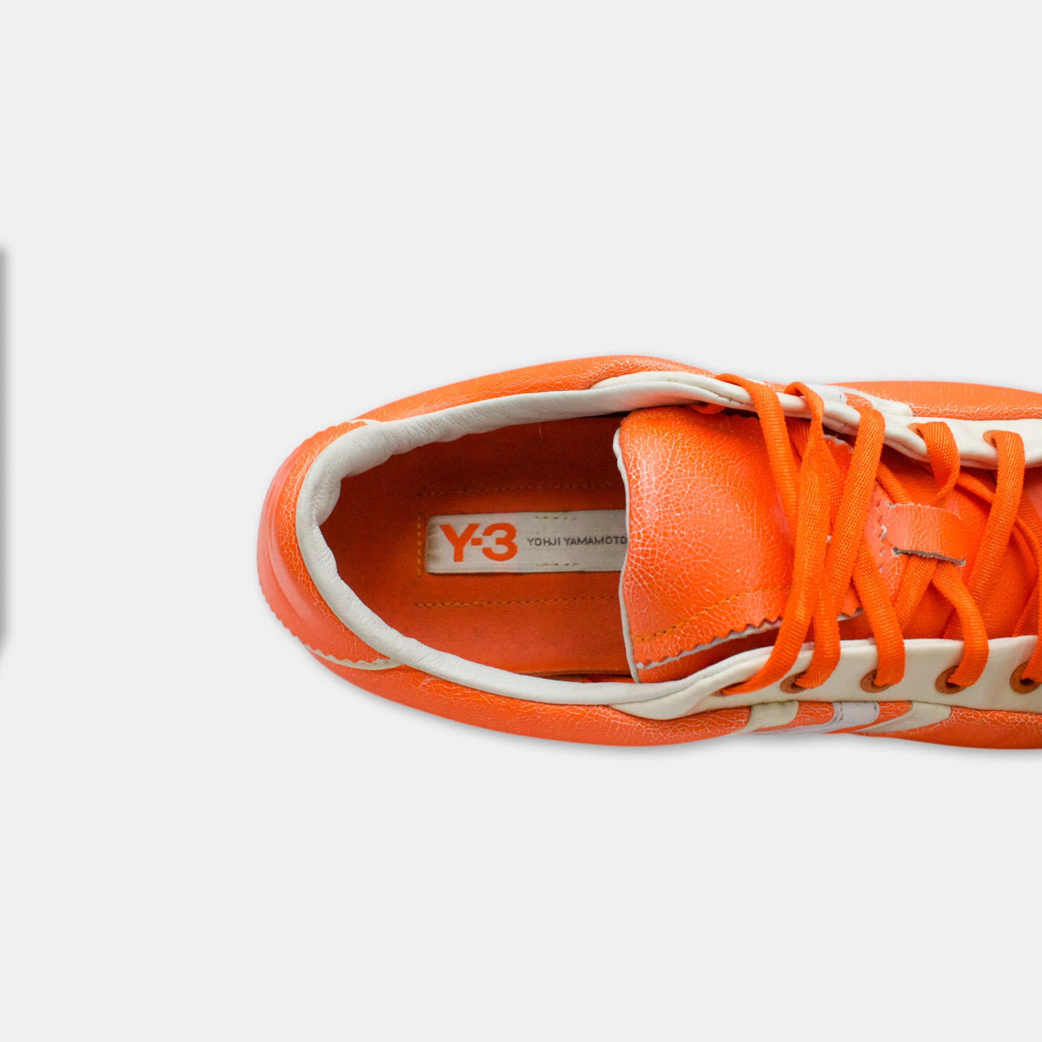 A close-up view of an orange and white sneaker, with the brand name "Y3" visible on the side.