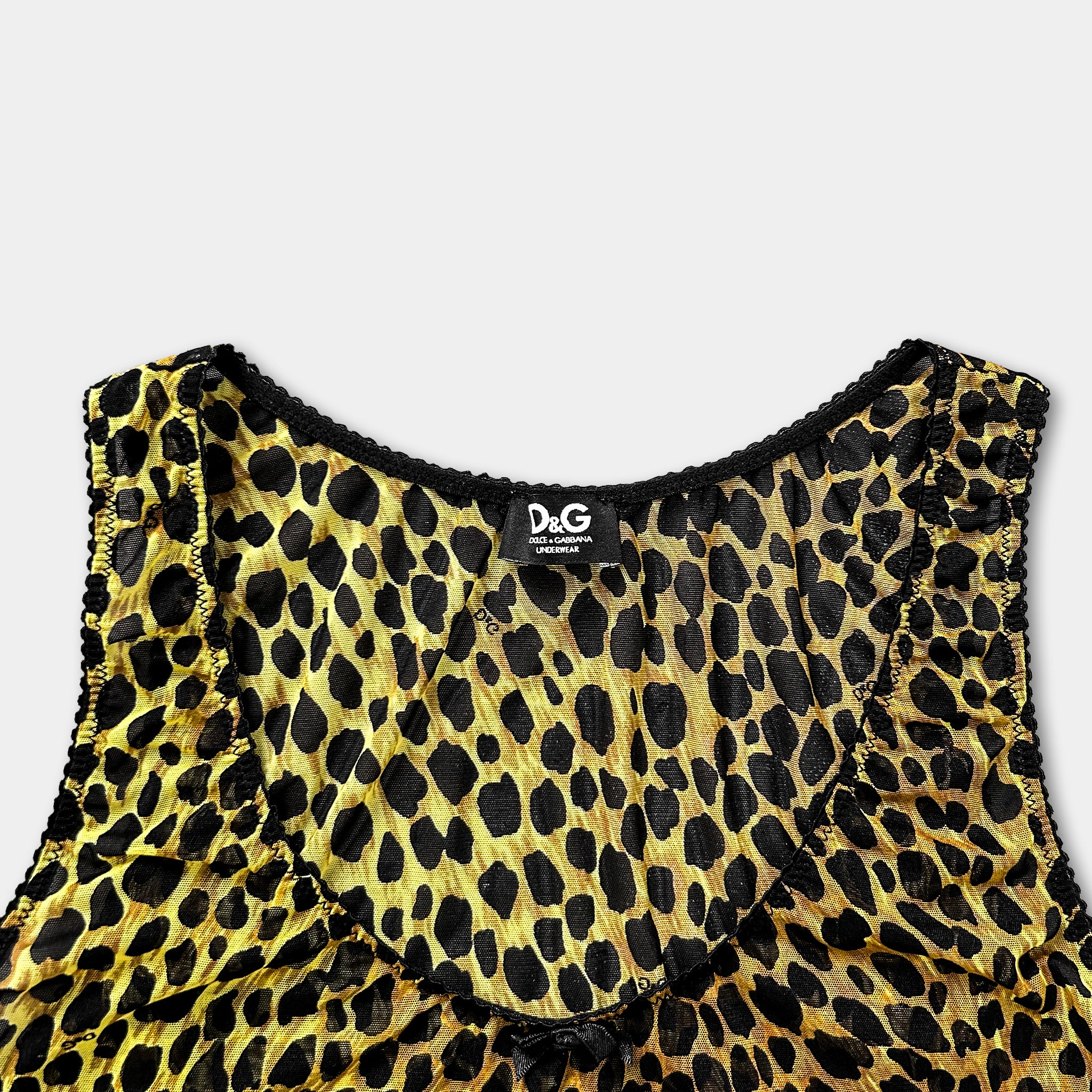 A close-up view of a yellow and black leopard print dress with a black collar and trim.