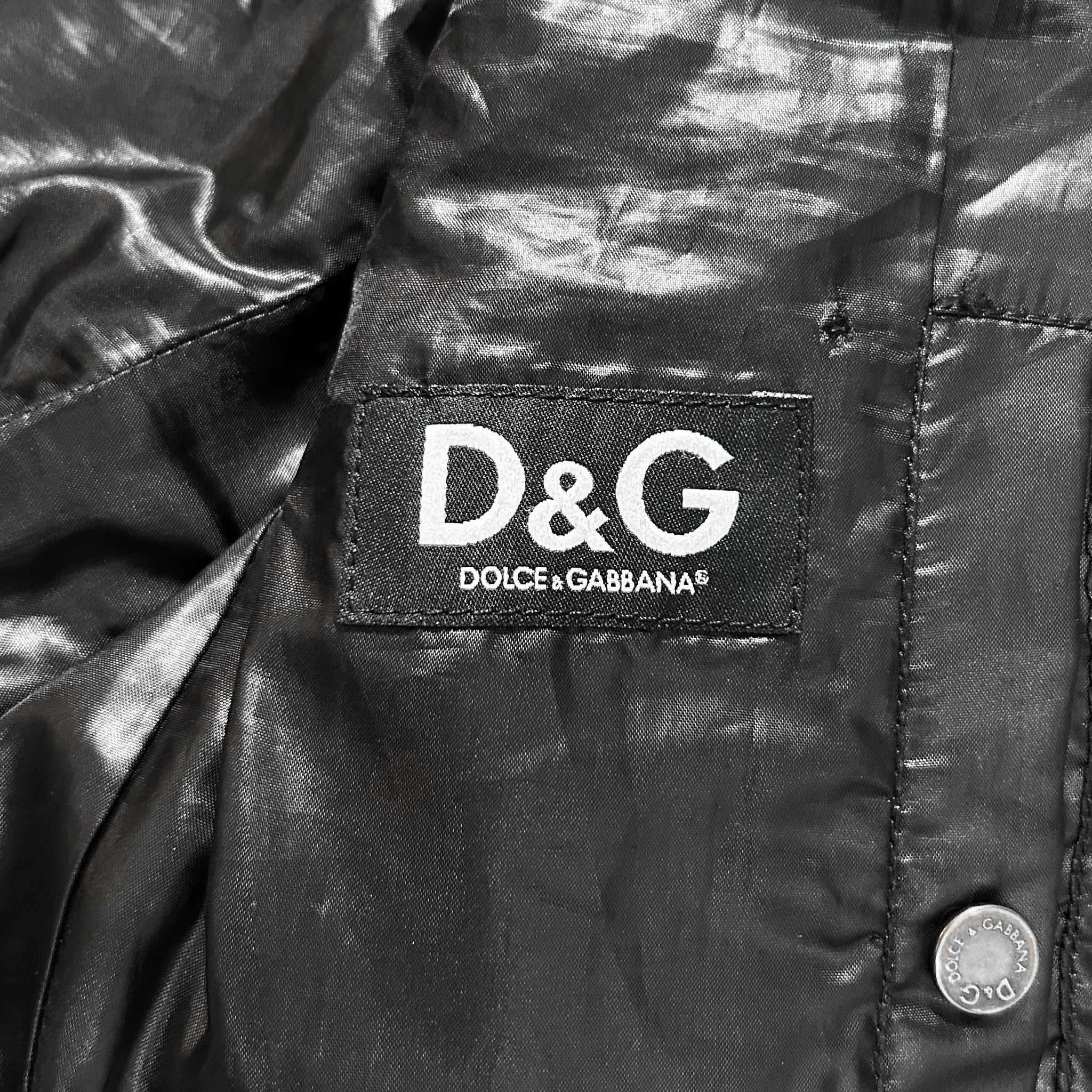 A close-up of a black leather jacket with a D&G logo on the left side.