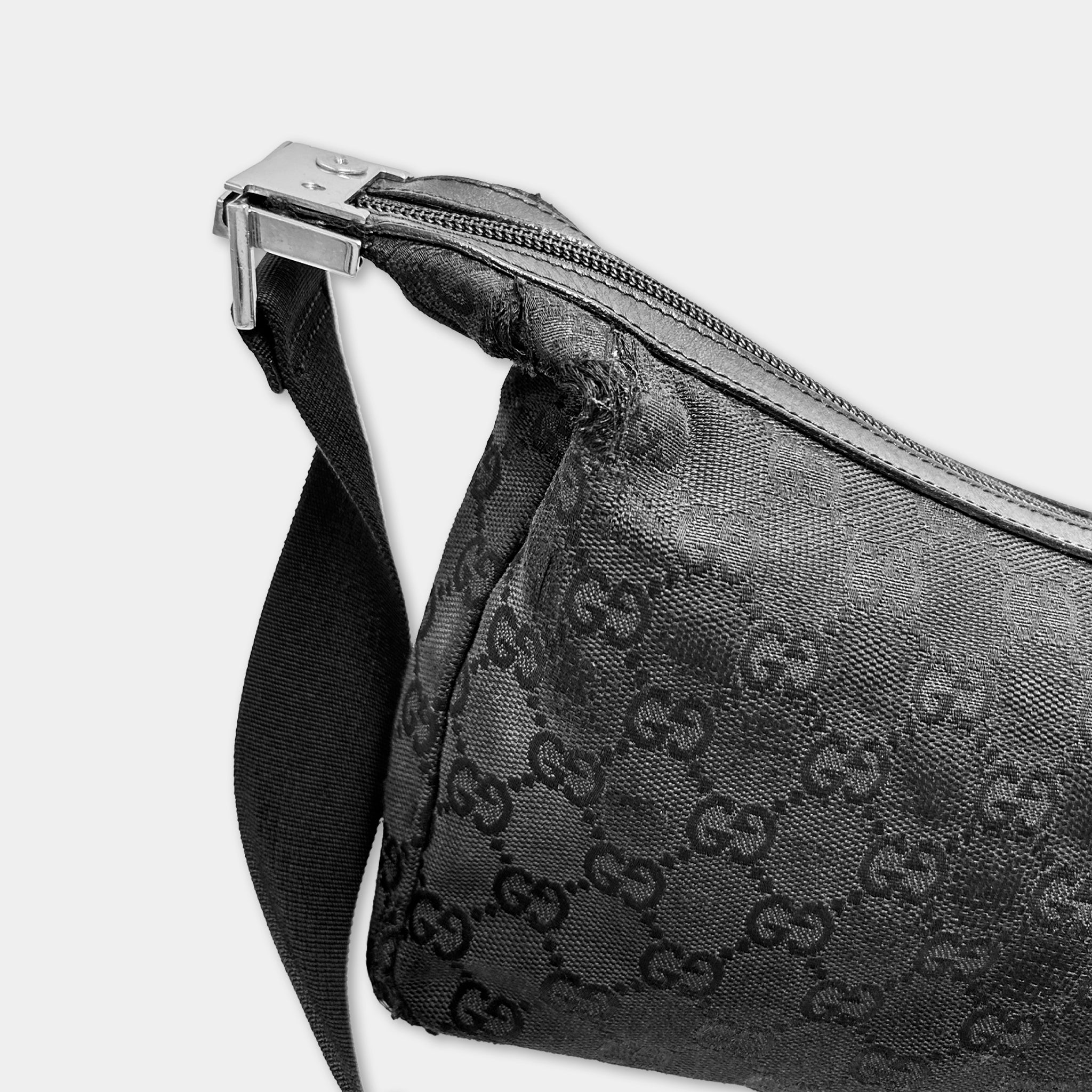 A close-up view of a black Gucci-patterned bag with a zipper closure.