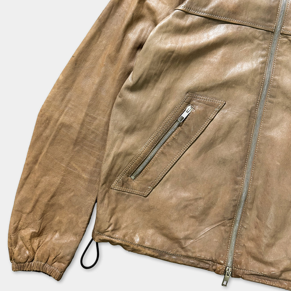 A close-up view of a tan leather jacket with a zipper pocket and a drawstring hood.