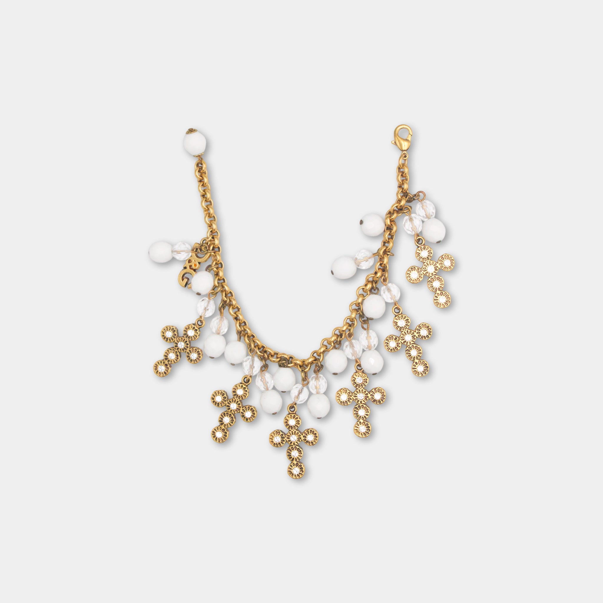 A gold-colored necklace with white beads and small crosses as charms.