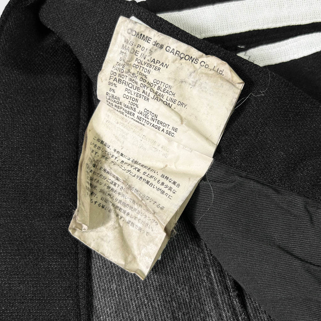 a close-up view of a torn label on a black fabric, with some text in a foreign language.