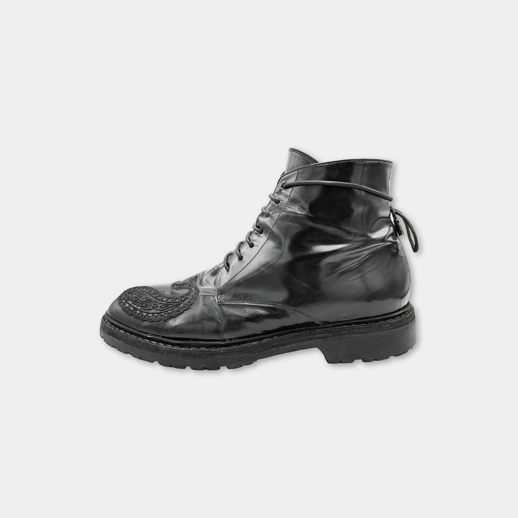 A shiny black leather boot with a lace-up closure and a textured sole.
