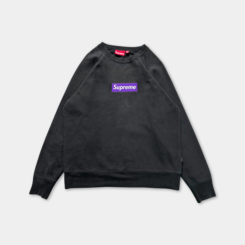 A black sweatshirt with a purple Supreme logo on the front.