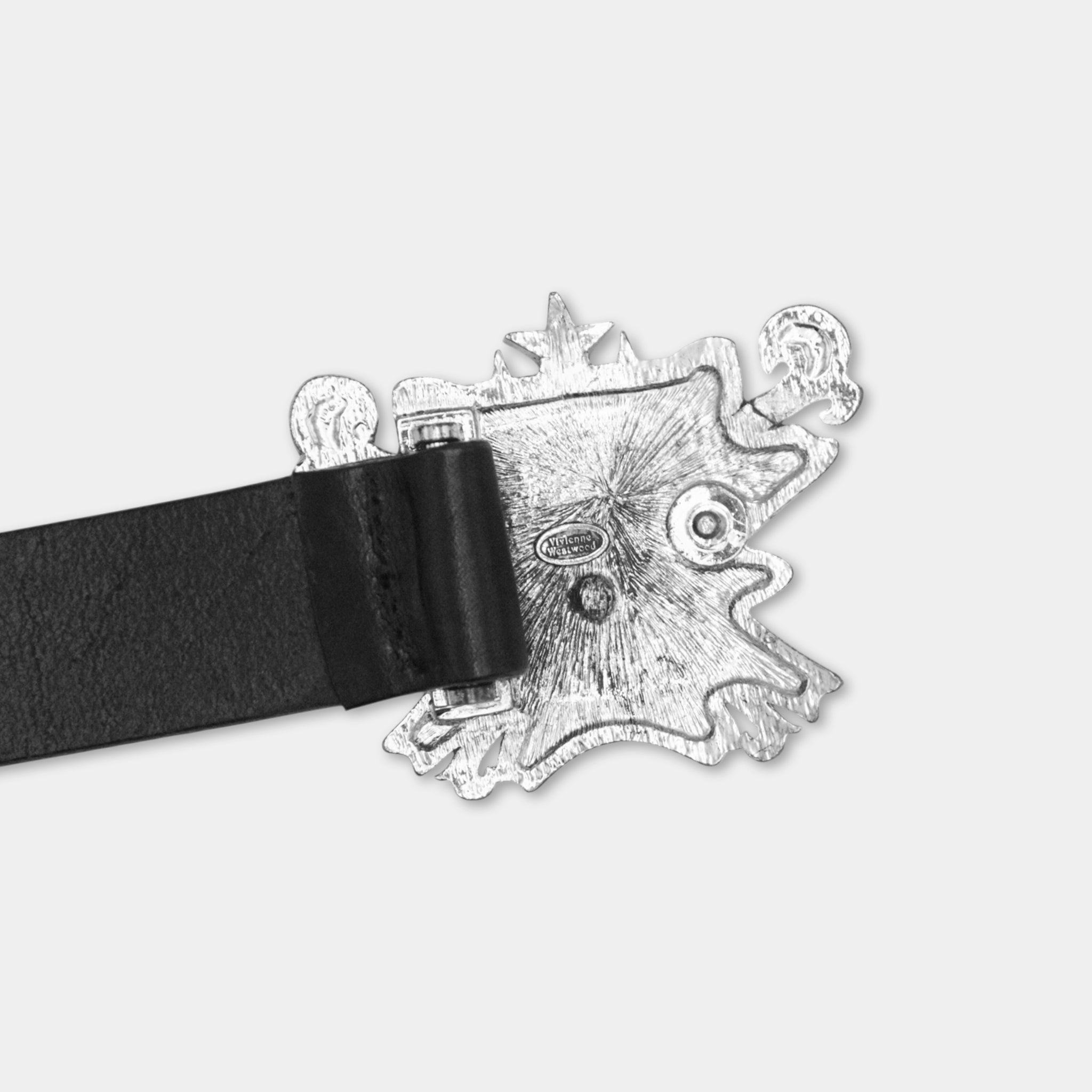 A close-up view of a black leather belt buckle with a decorative metal design.