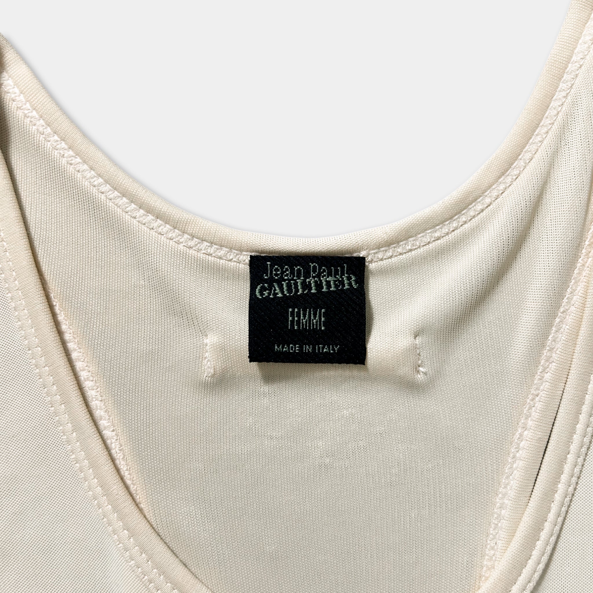 a close-up view of a white fabric, possibly a piece of clothing, with a label attached to it. The label appears to be a tag or label, possibly indicating the brand or manufacturer of the fabric.