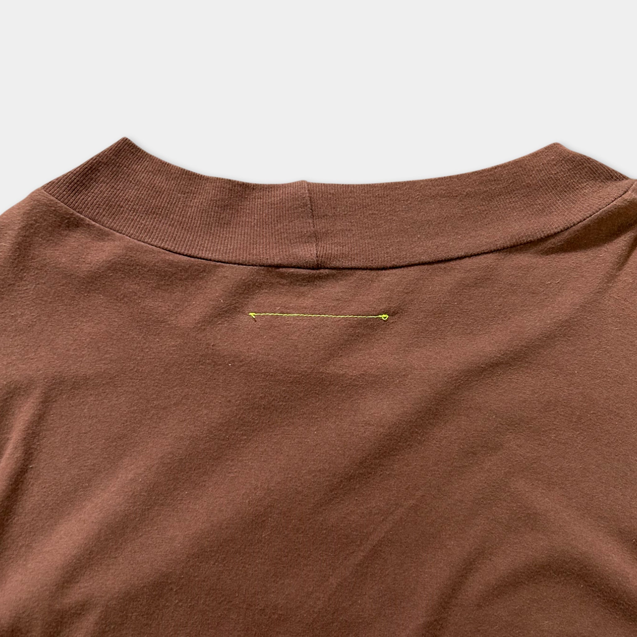 a close-up view of a brown t-shirt with a small yellow line running down the center of the shirt.