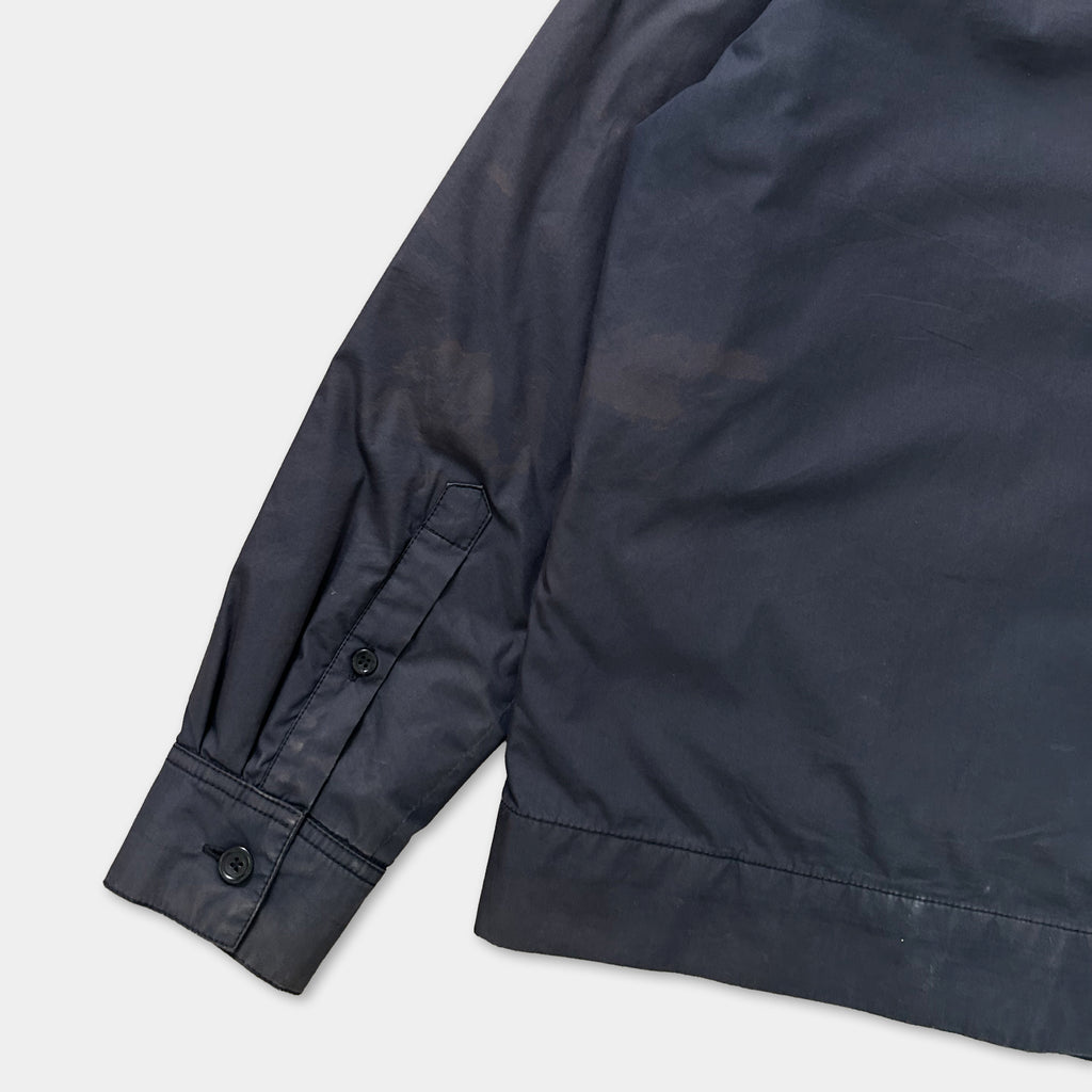 A close-up view of a dark-colored jacket sleeve, showing the fabric and buttons.