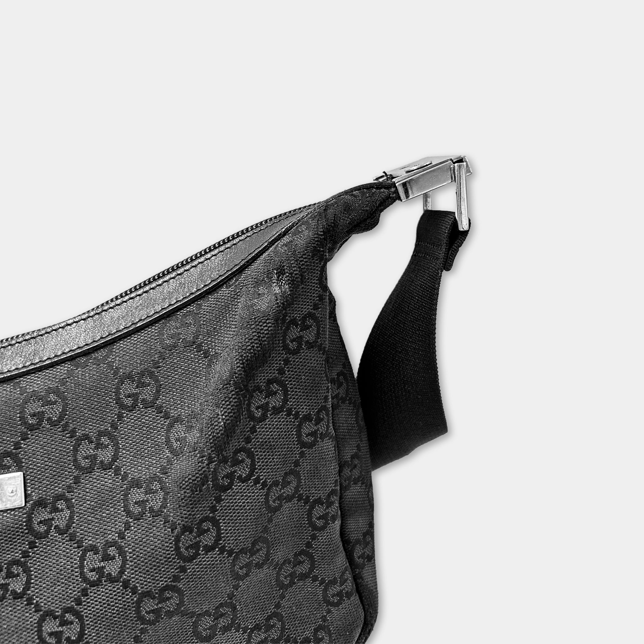 A close-up view of a black Gucci handbag with a distinctive monogram pattern.