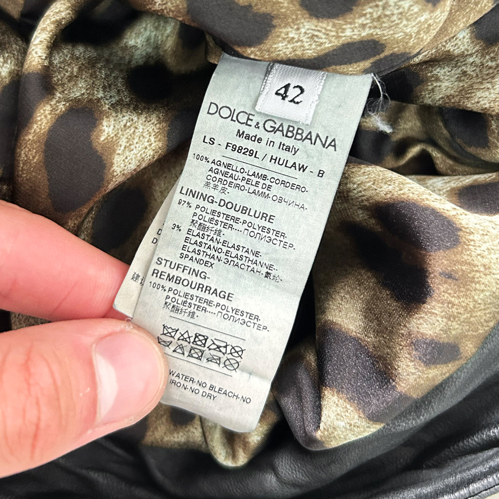 A close-up of a hand holding a label from a garment, with a leopard print pattern visible.