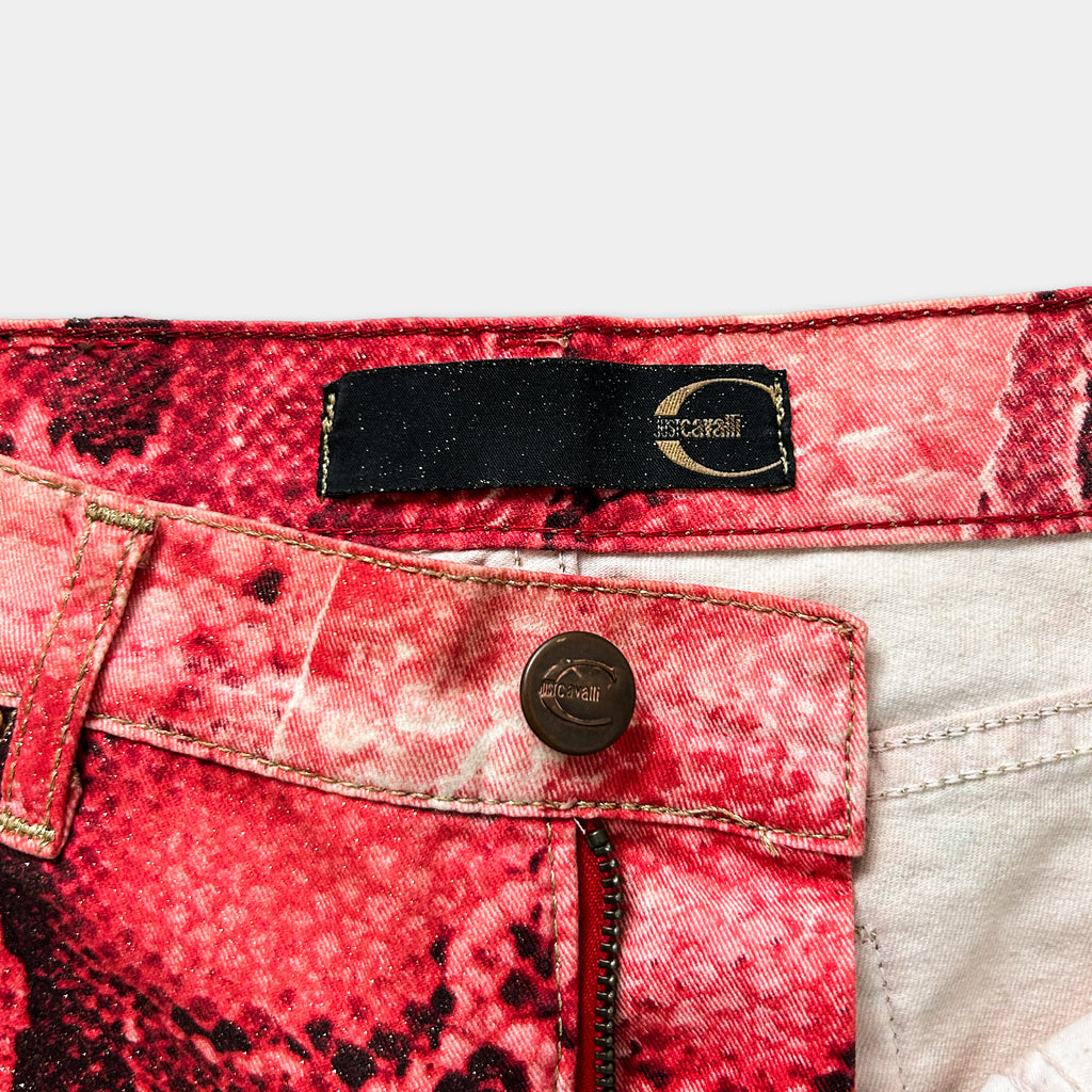 a close-up view of a pair of red and white patterned jeans, with a black label or tag attached to the waistband.