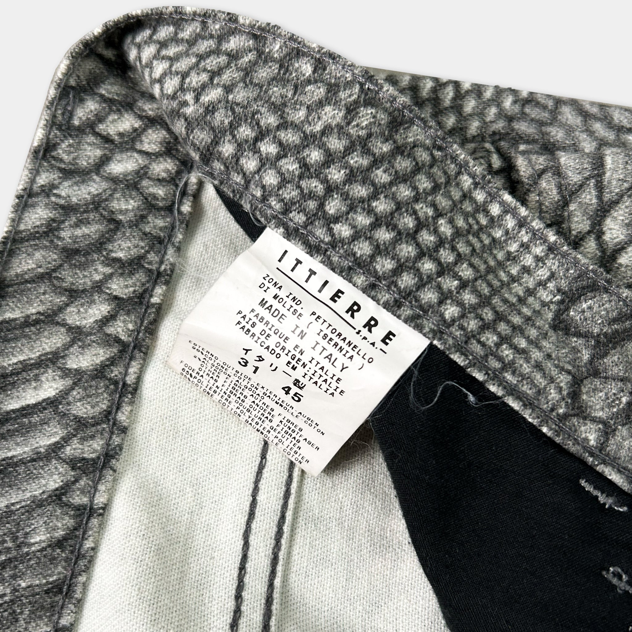a close-up view of a label attached to a pair of pants, with a patterned fabric visible.
