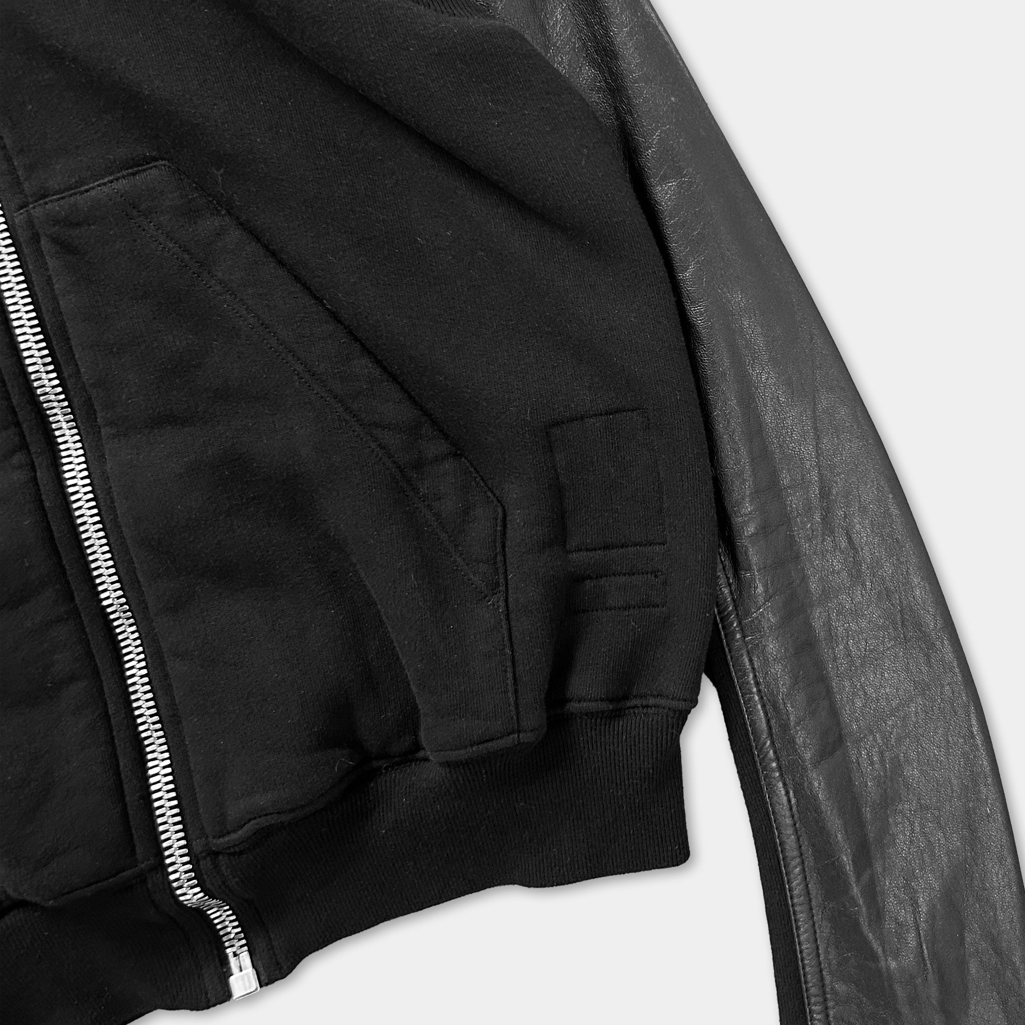 A close-up view of a black zip-up jacket with a zipper and a pocket.