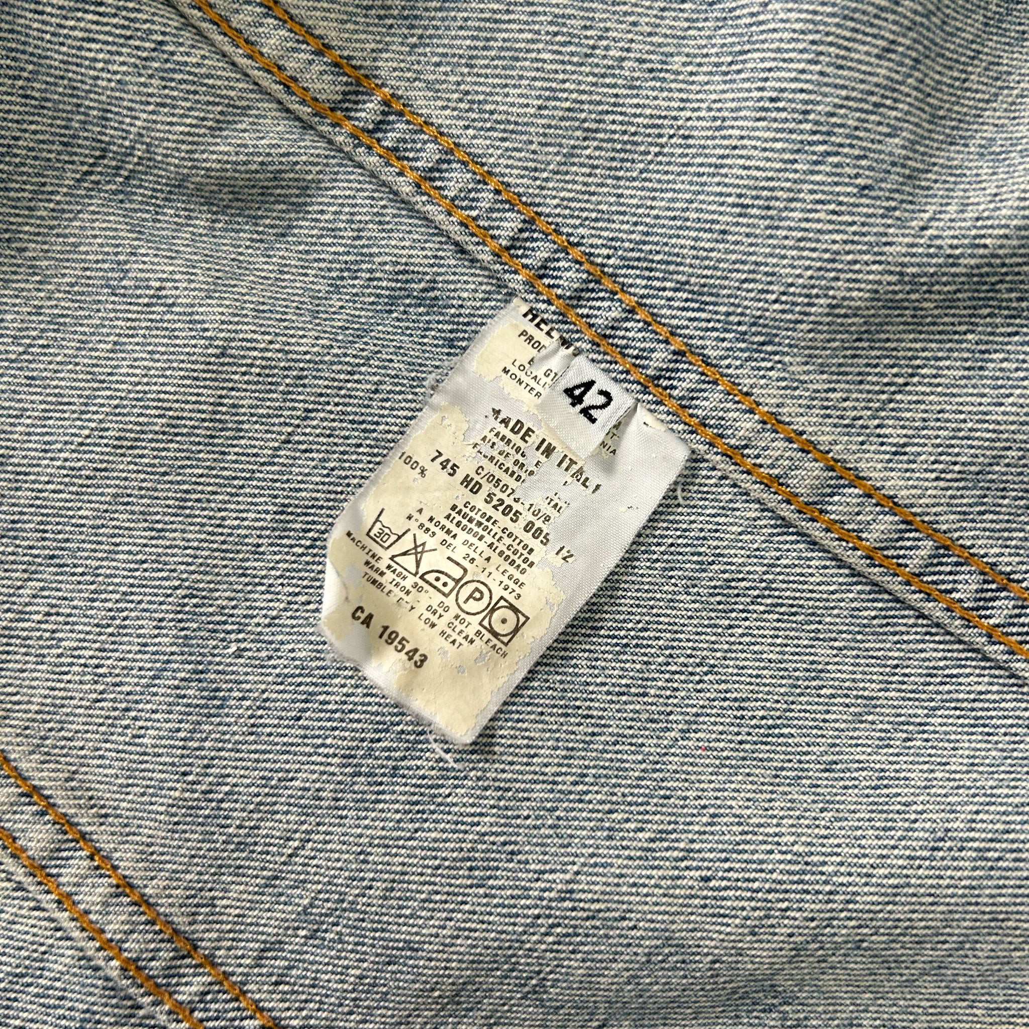 a close-up view of a denim fabric, specifically a pair of jeans, with a label attached to it. The label appears to contain information about the jeans, such as the brand, size, and care instructions.