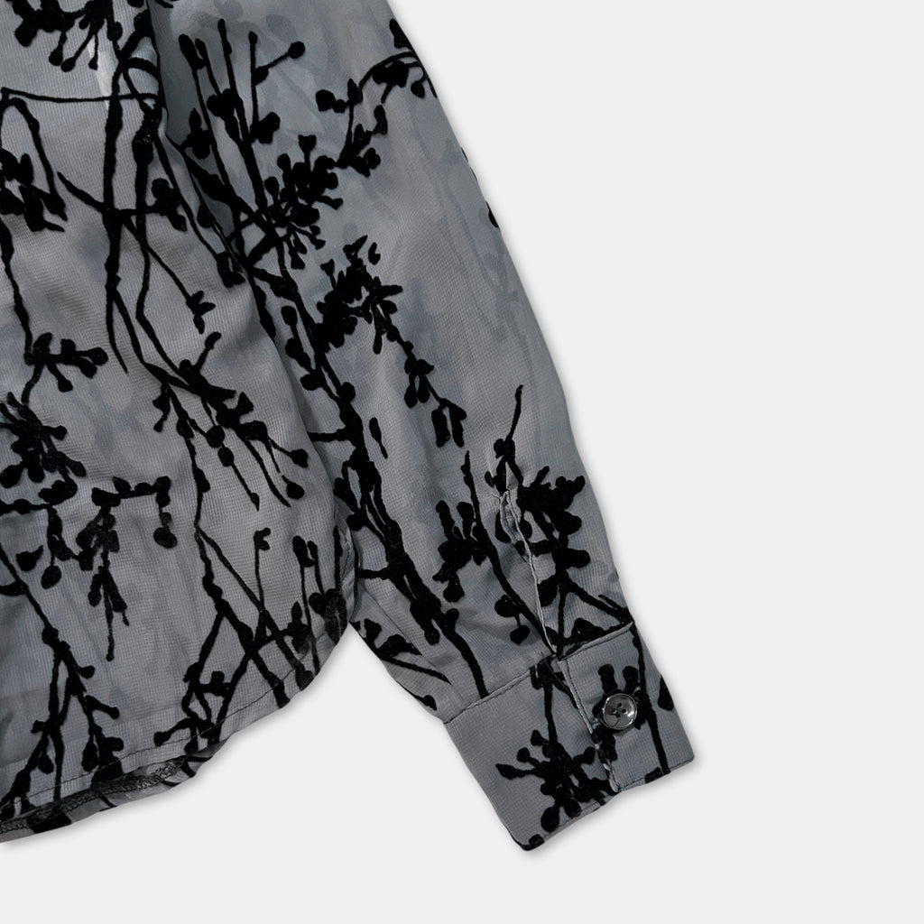 a close-up view of a gray shirt with a black floral pattern on the sleeve.