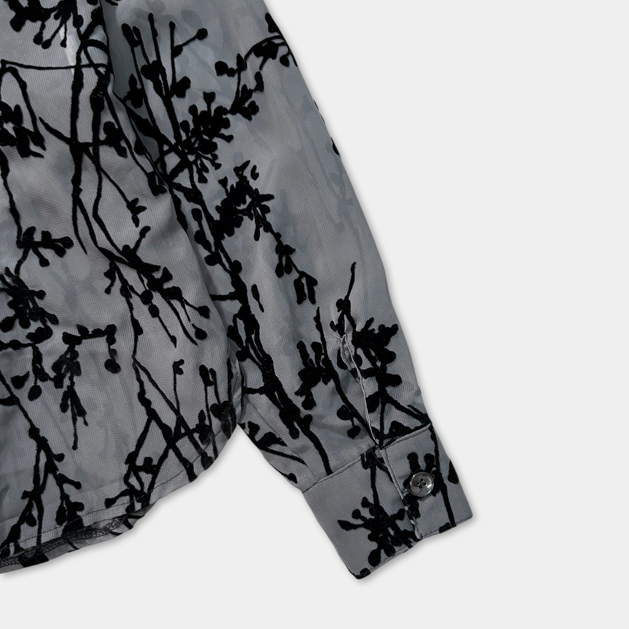 a close-up view of a gray shirt with a black floral pattern on the sleeve.