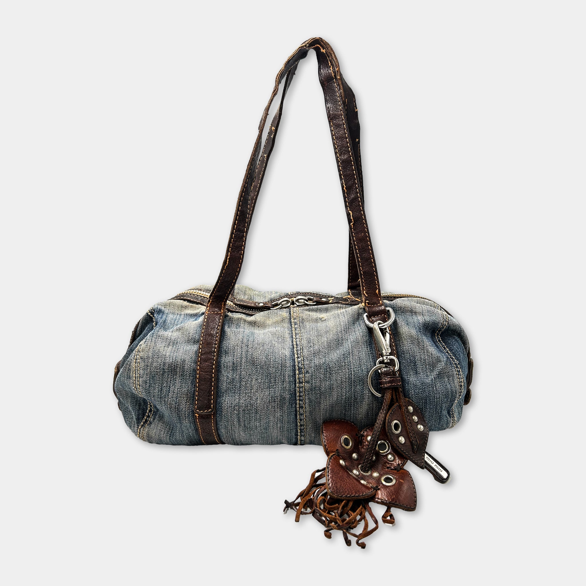 A blue denim purse with a leather strap and a metal clasp.