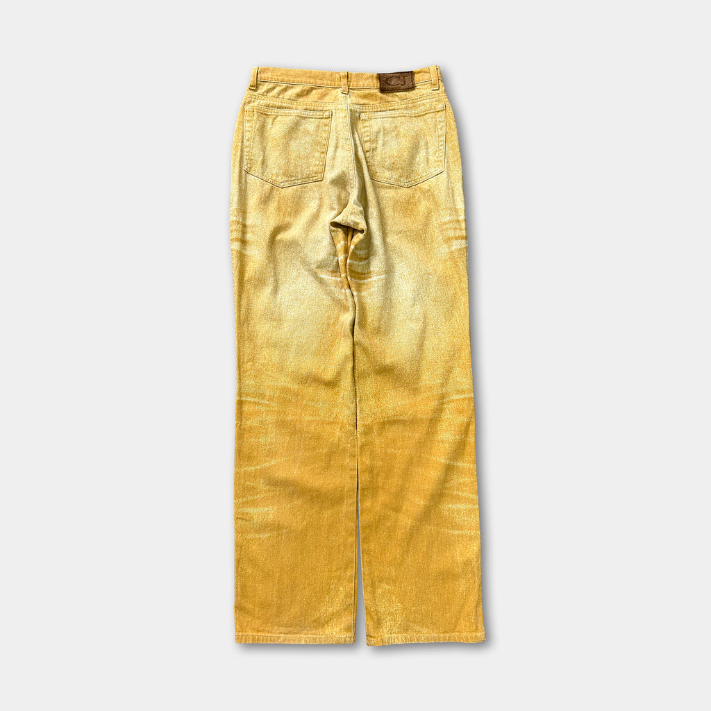 A pair of yellow-colored jeans with a faded, distressed appearance.