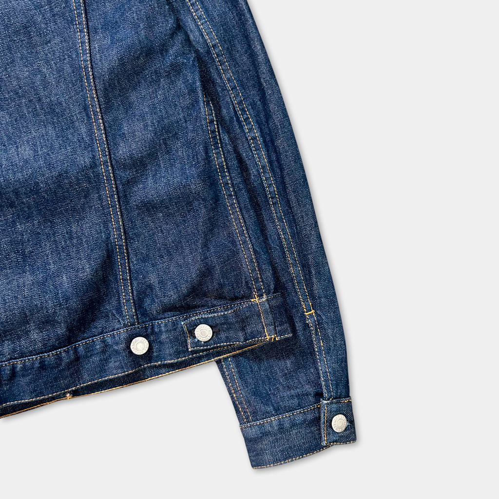 A close-up view of a blue denim jacket with a zipper and buttons, against a plain white background.