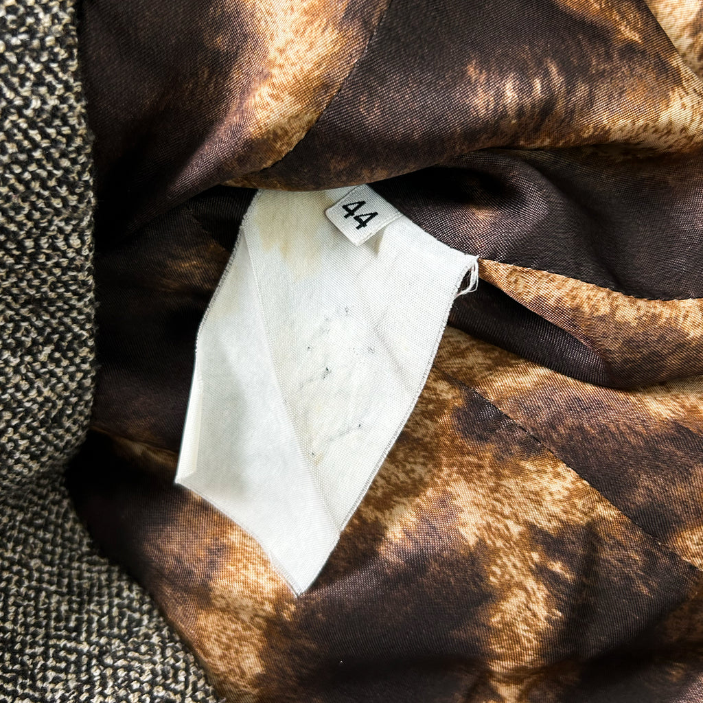 a close-up view of a fabric with a brown and black pattern, and a white label attached to it.