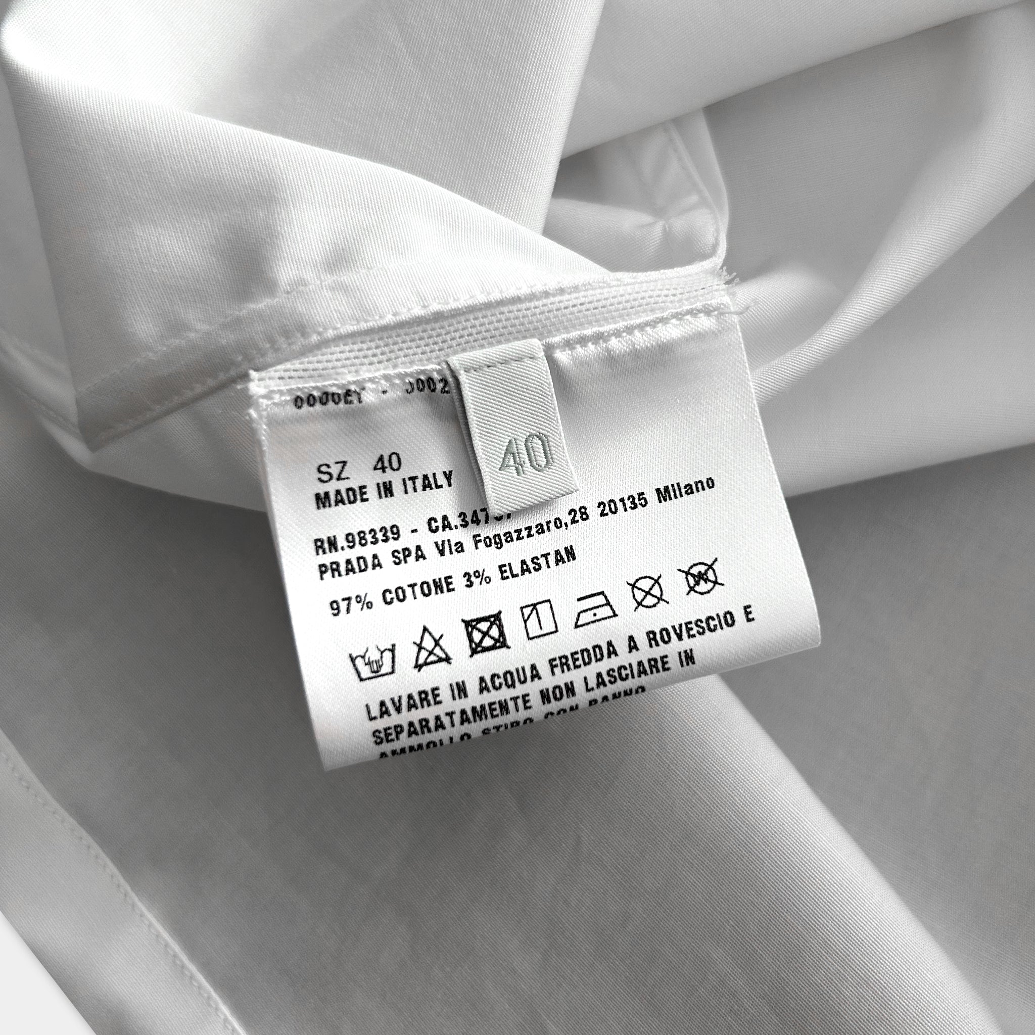 a close-up of a white fabric label with text and symbols, indicating the material and care instructions for the garment.