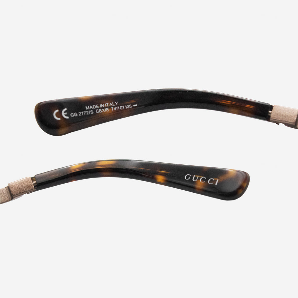 a pair of tortoiseshell-framed sunglasses with the Gucci logo visible on the frame.