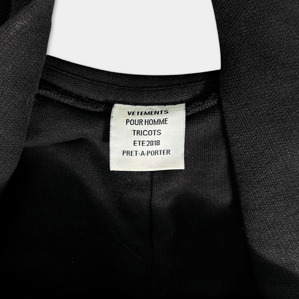 a close-up view of a black jacket with a label attached to it.