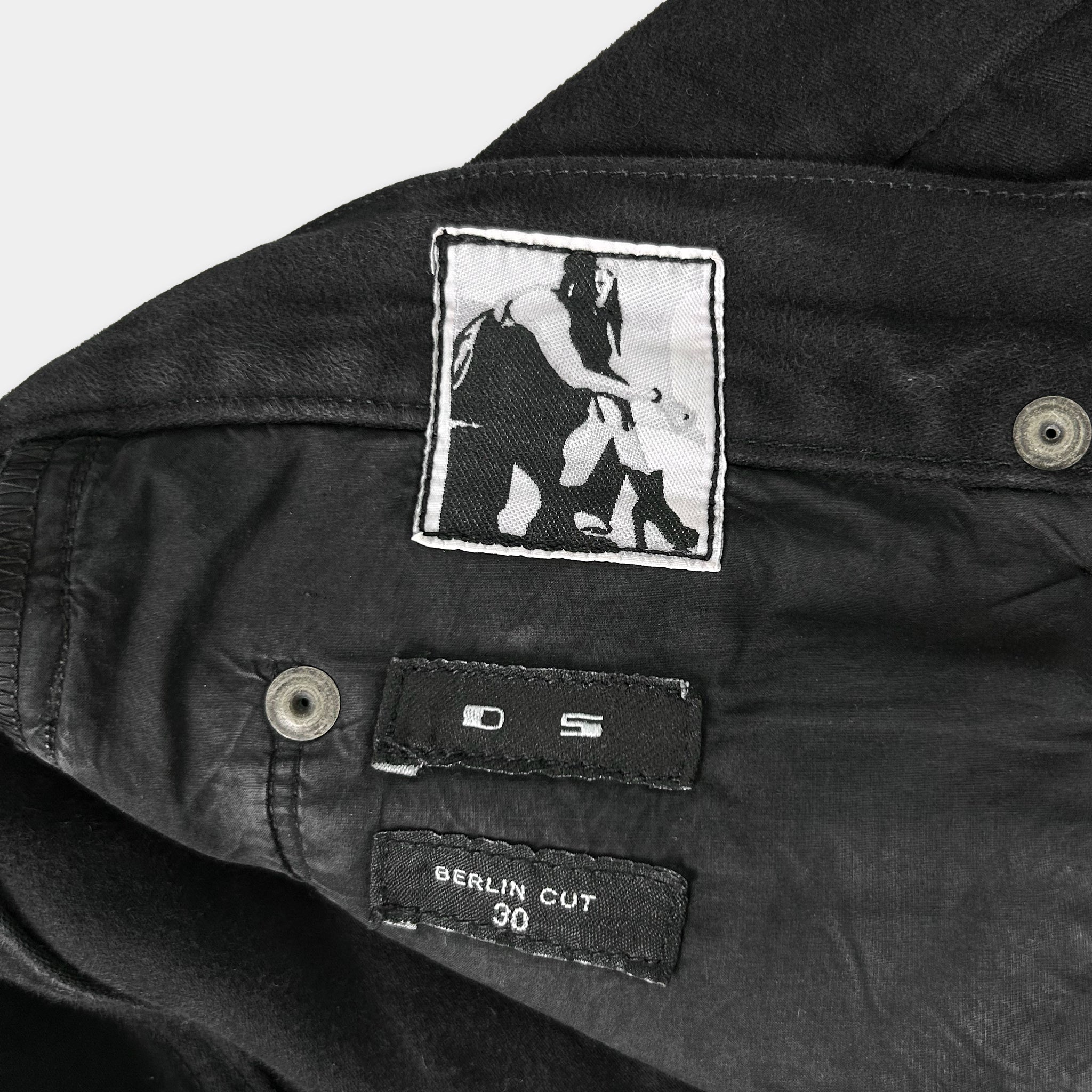 a close-up view of a pair of black pants with a label and a patch on the pocket.