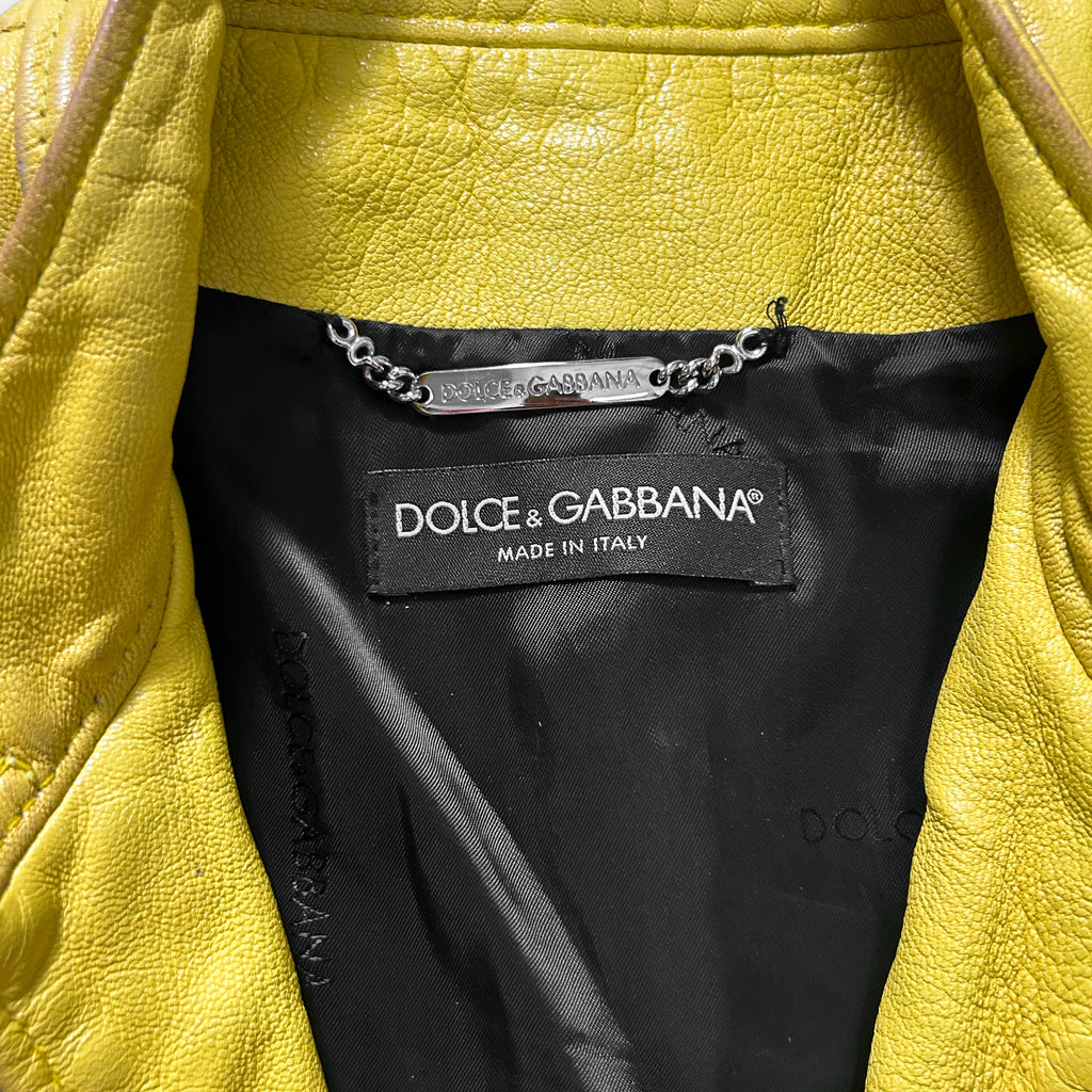 a close-up view of a yellow leather jacket with a black label on the inside, indicating it is a Dolce & Gabbana product.