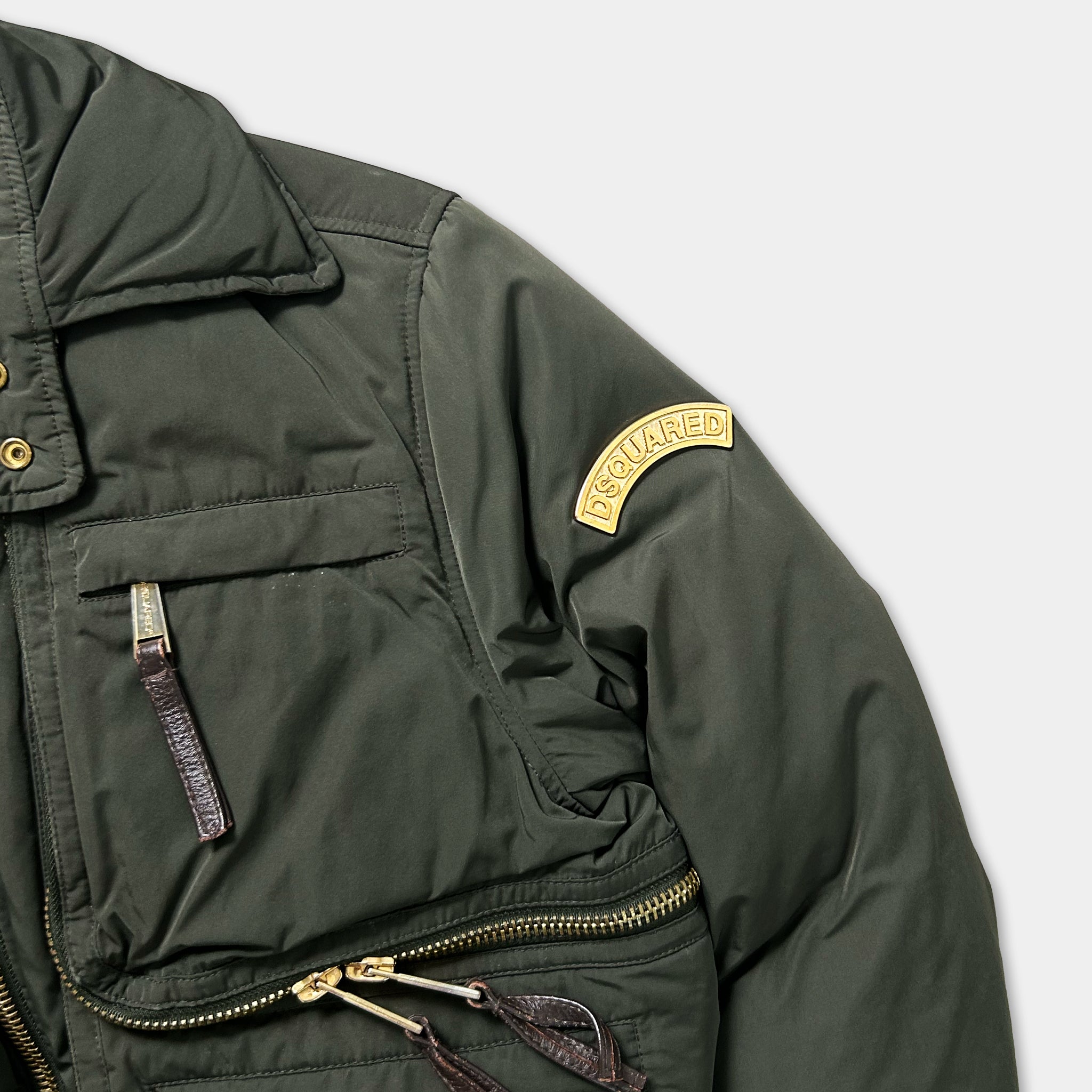 A close-up view of a dark green puffy jacket with a yellow patch on the left arm.