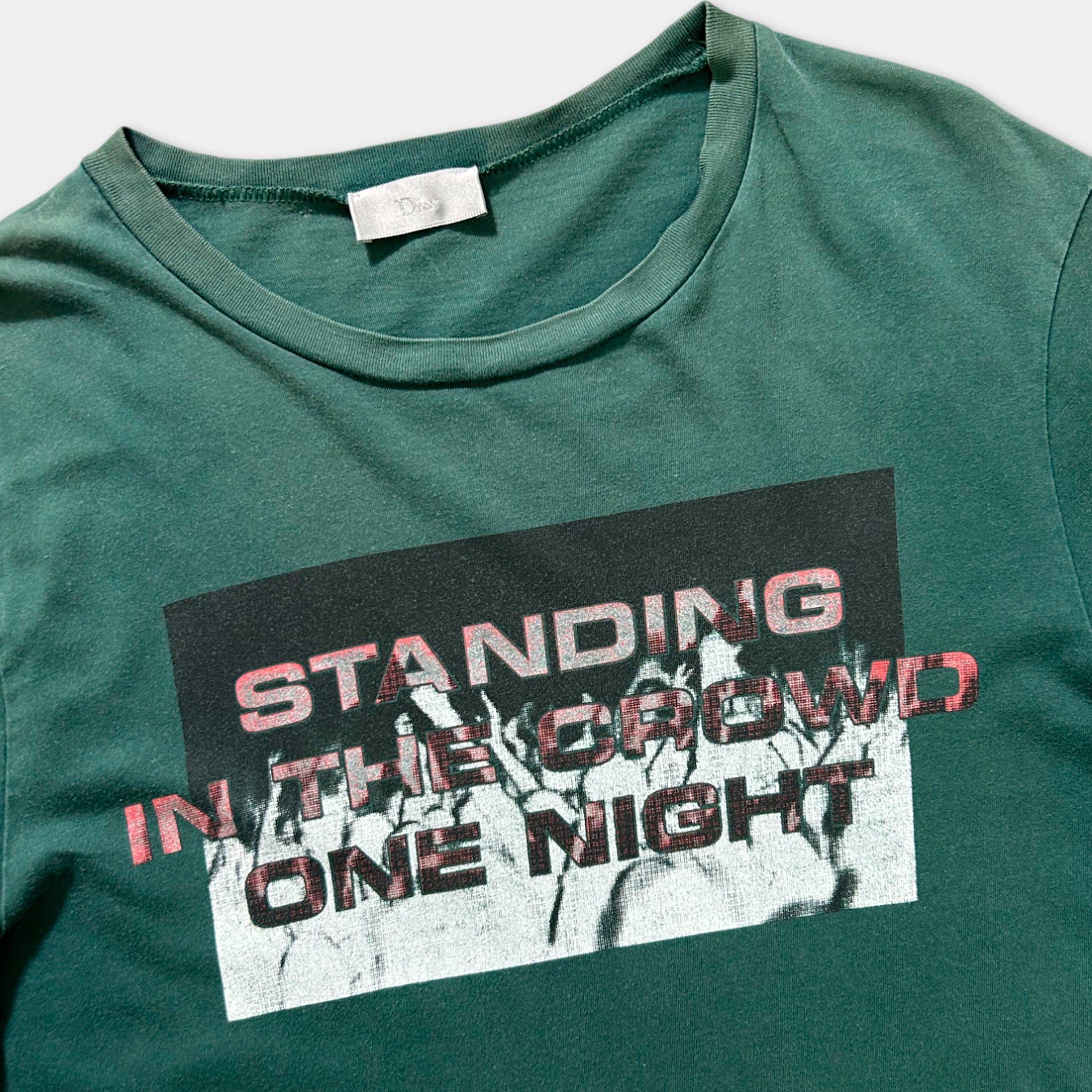 A green t-shirt with a graphic design featuring the text "STANDING IN THE GROWD ONE NIGHT" printed on it.