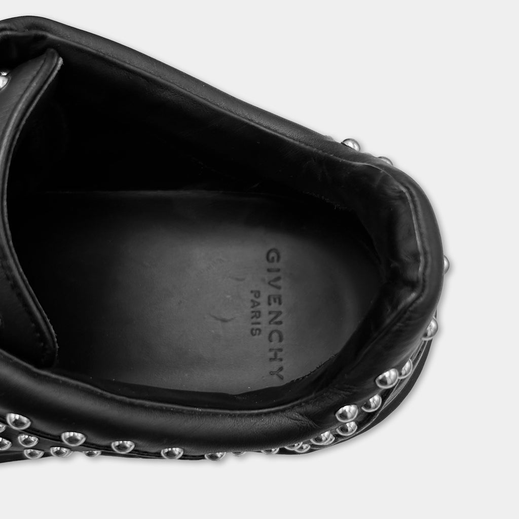 A close-up view of a black leather shoe with silver studs on the side.