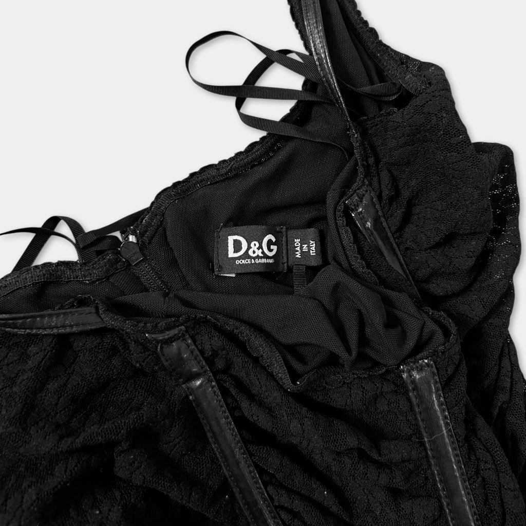 A close-up view of a black lace dress with a label on the back.