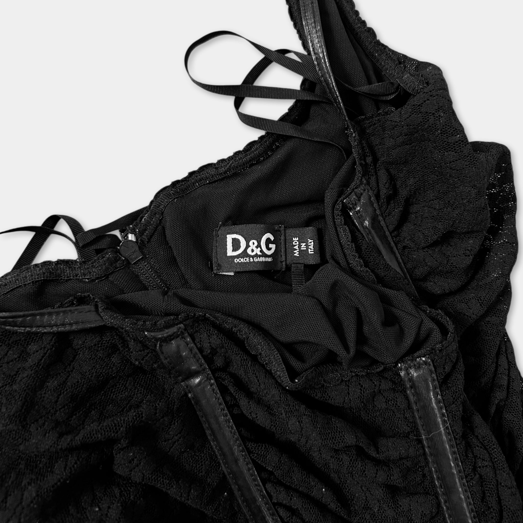 A close-up view of a black lace dress with a label on the back.