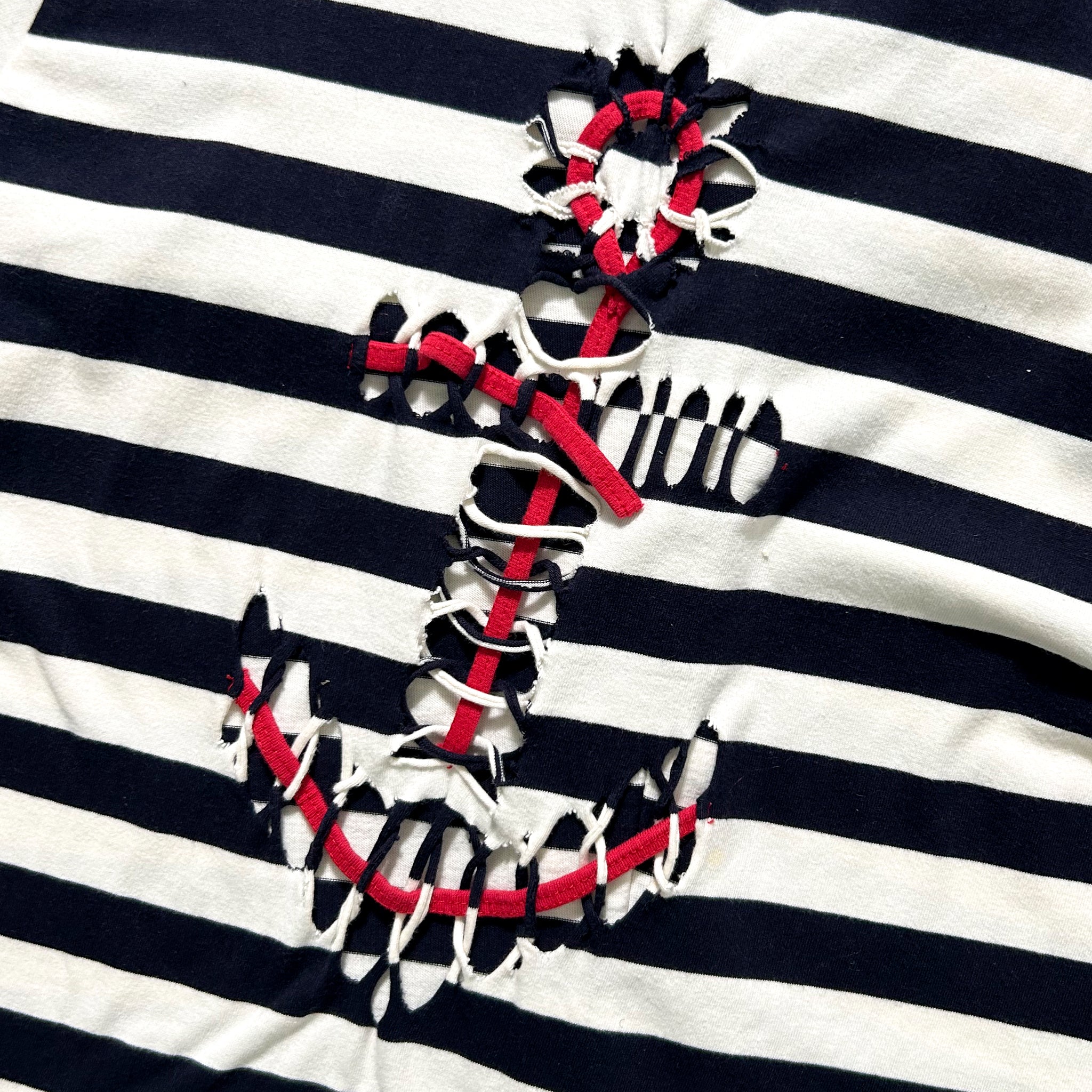 a close-up view of a black and white striped fabric with a red and white braided anchor design prominently displayed on it.