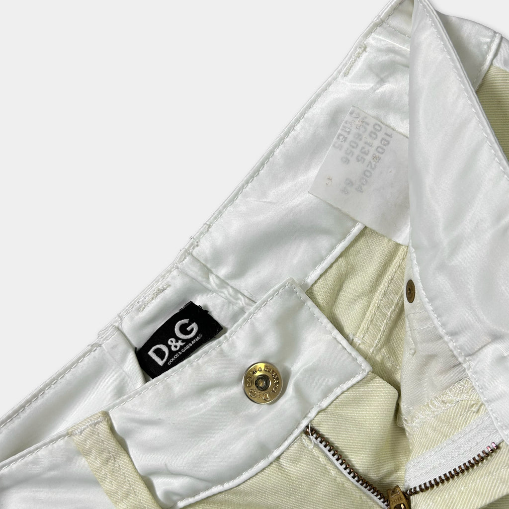 A close-up view of a pair of white pants with a label attached to the waistband.