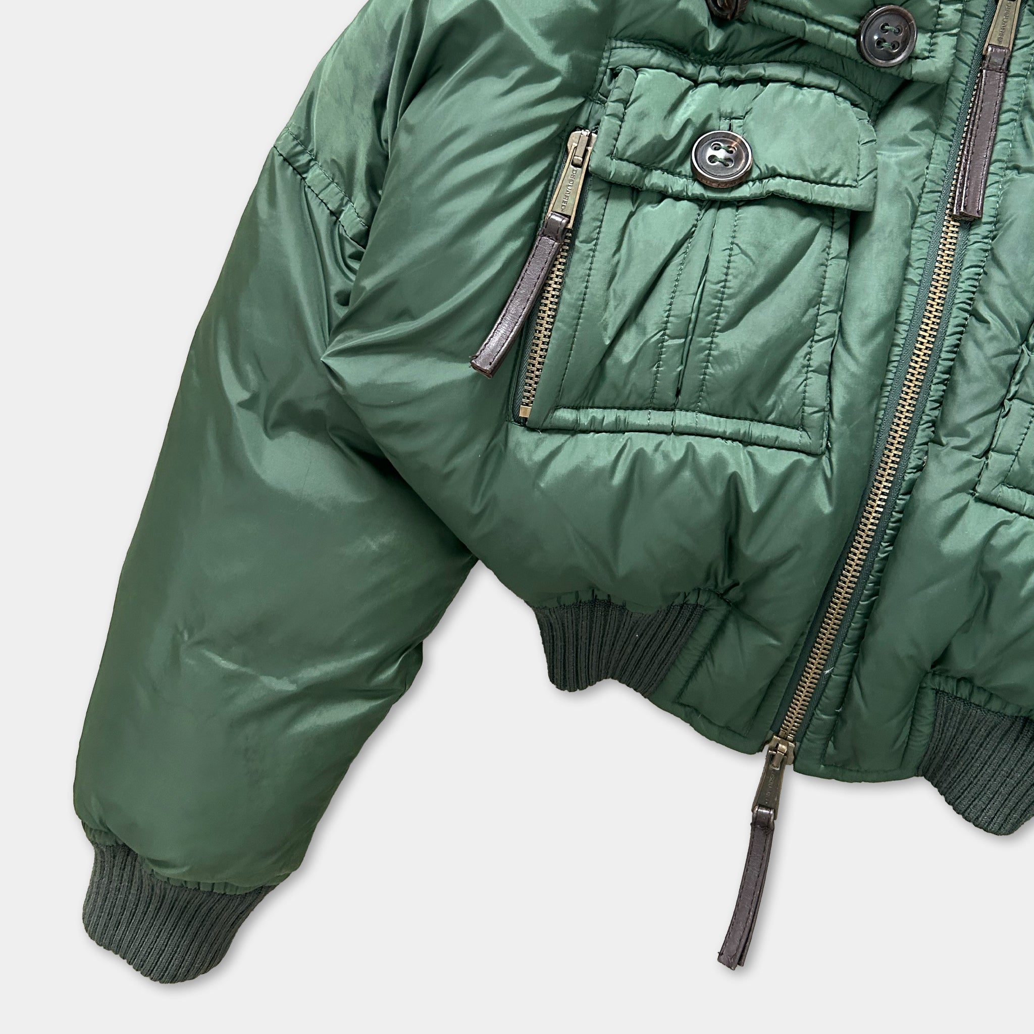 A close-up view of a green puffy jacket with a zipper and pockets.