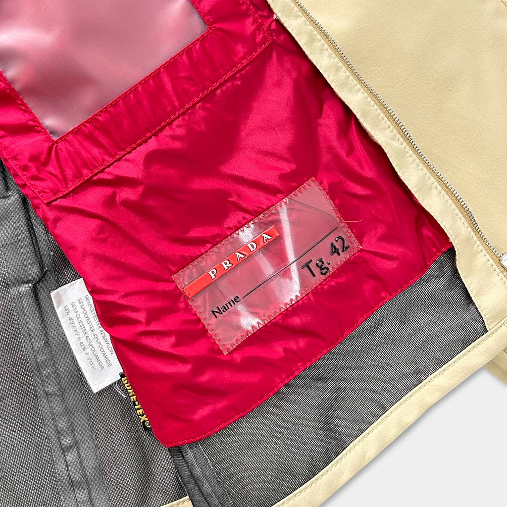 a red Prada jacket with a label that includes the brand name and a name tag.