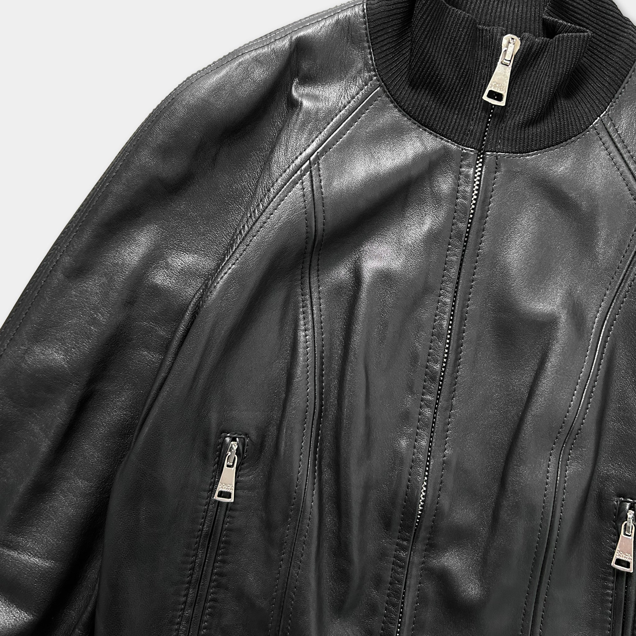A close-up view of a black leather jacket with a zipper and a collar.