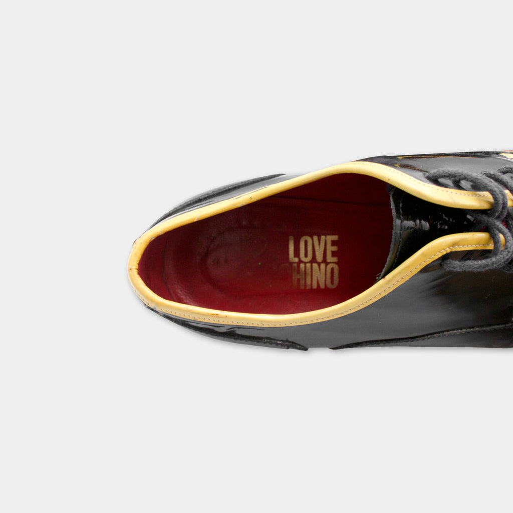 A close-up view of a black and gold shoe with the word "LOVE" printed on the inside of the shoe.