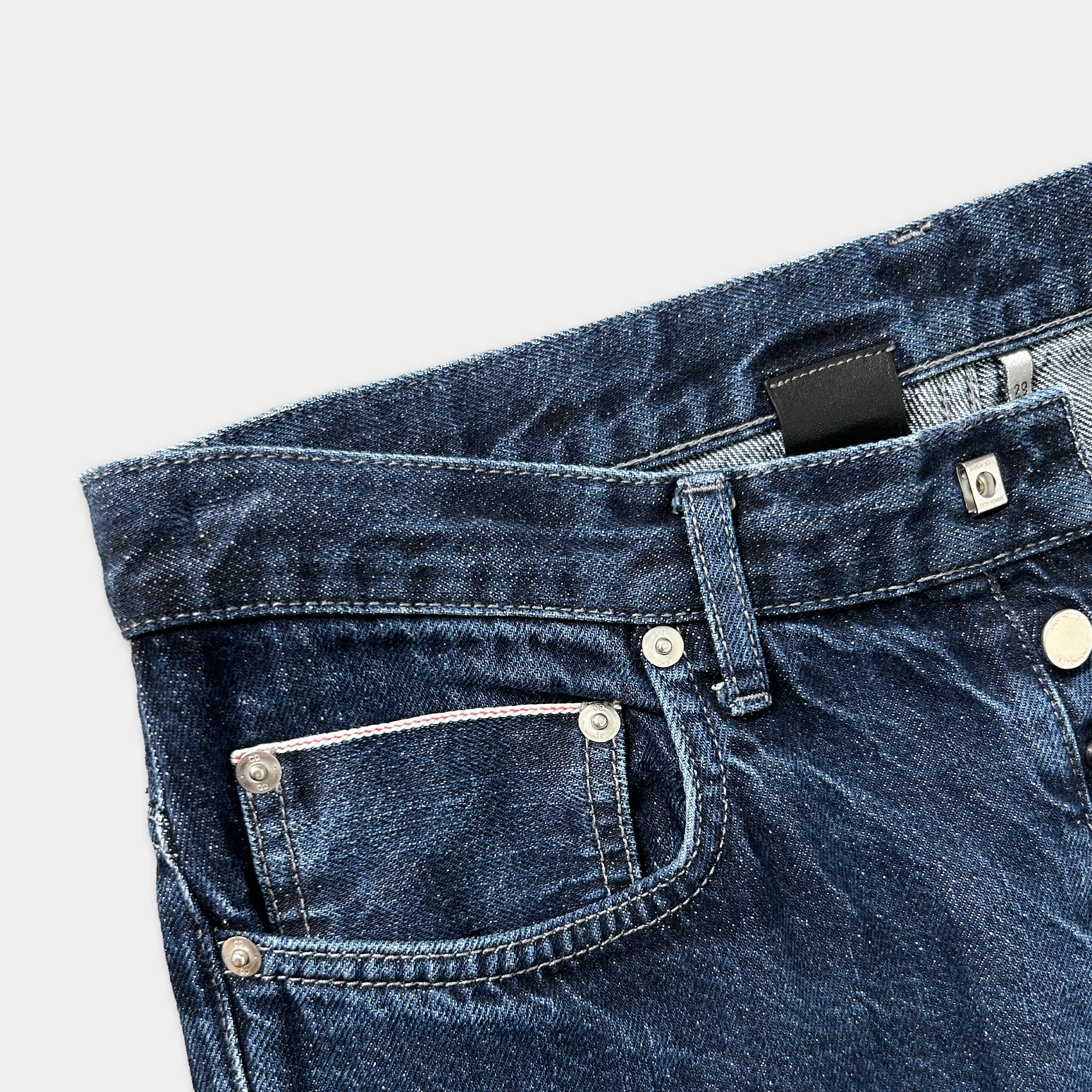 A close-up view of a pair of blue jeans with a pocket and a zipper.
