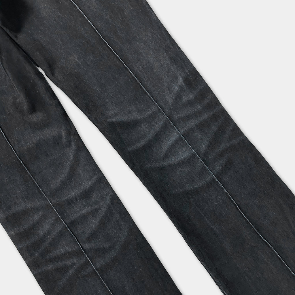 A close-up view of a pair of black jeans, showing the fabric and stitching.