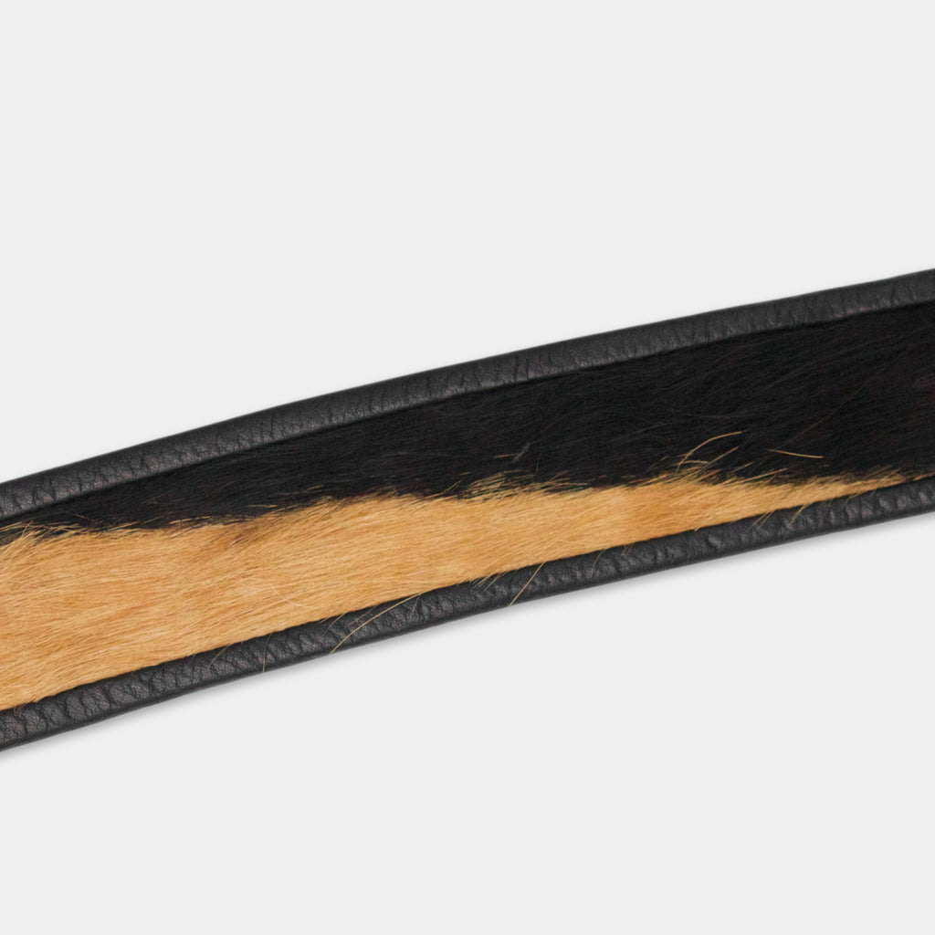 A close-up view of a black and tan leather belt with a distinctive pattern.