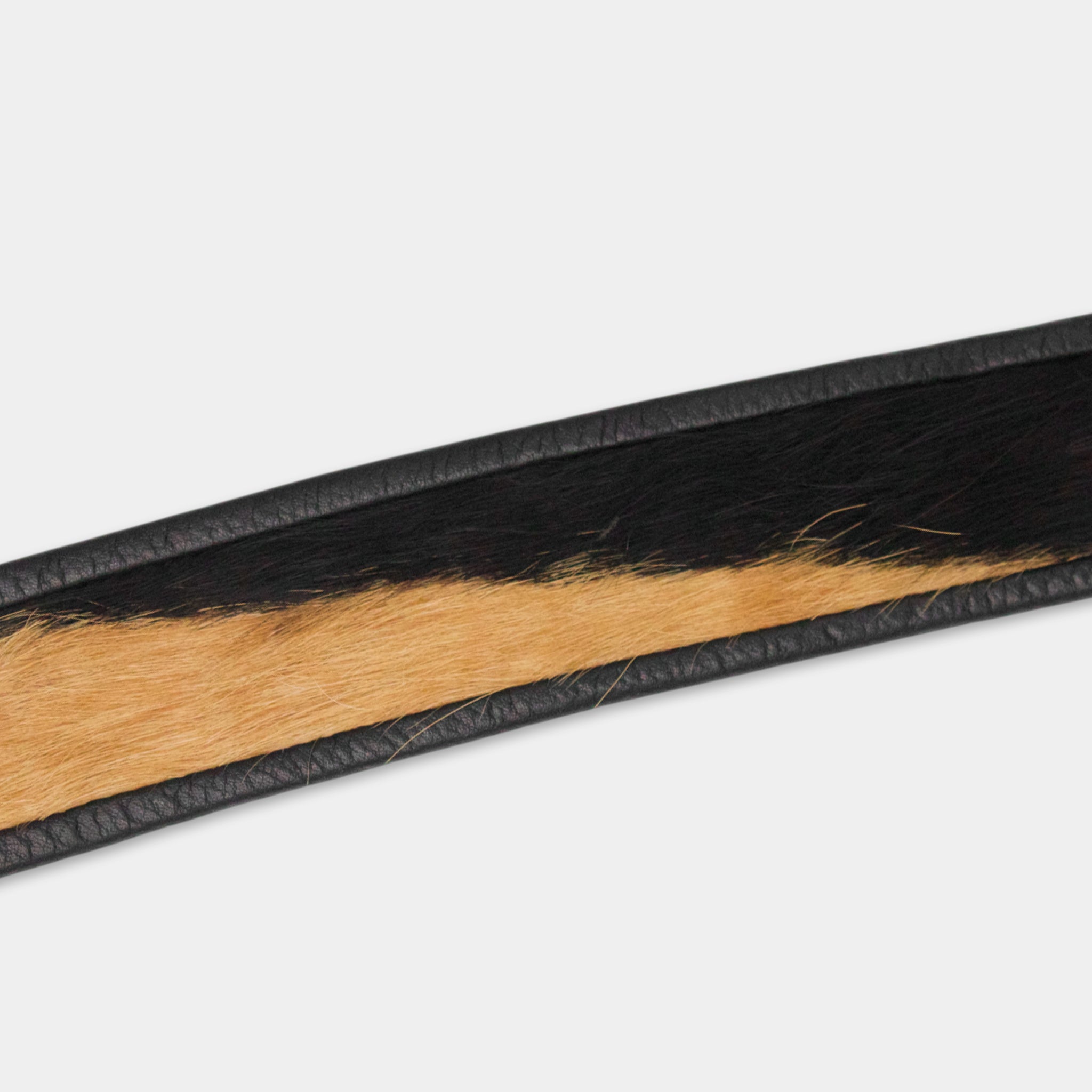A close-up view of a black and tan leather belt with a distinctive pattern.