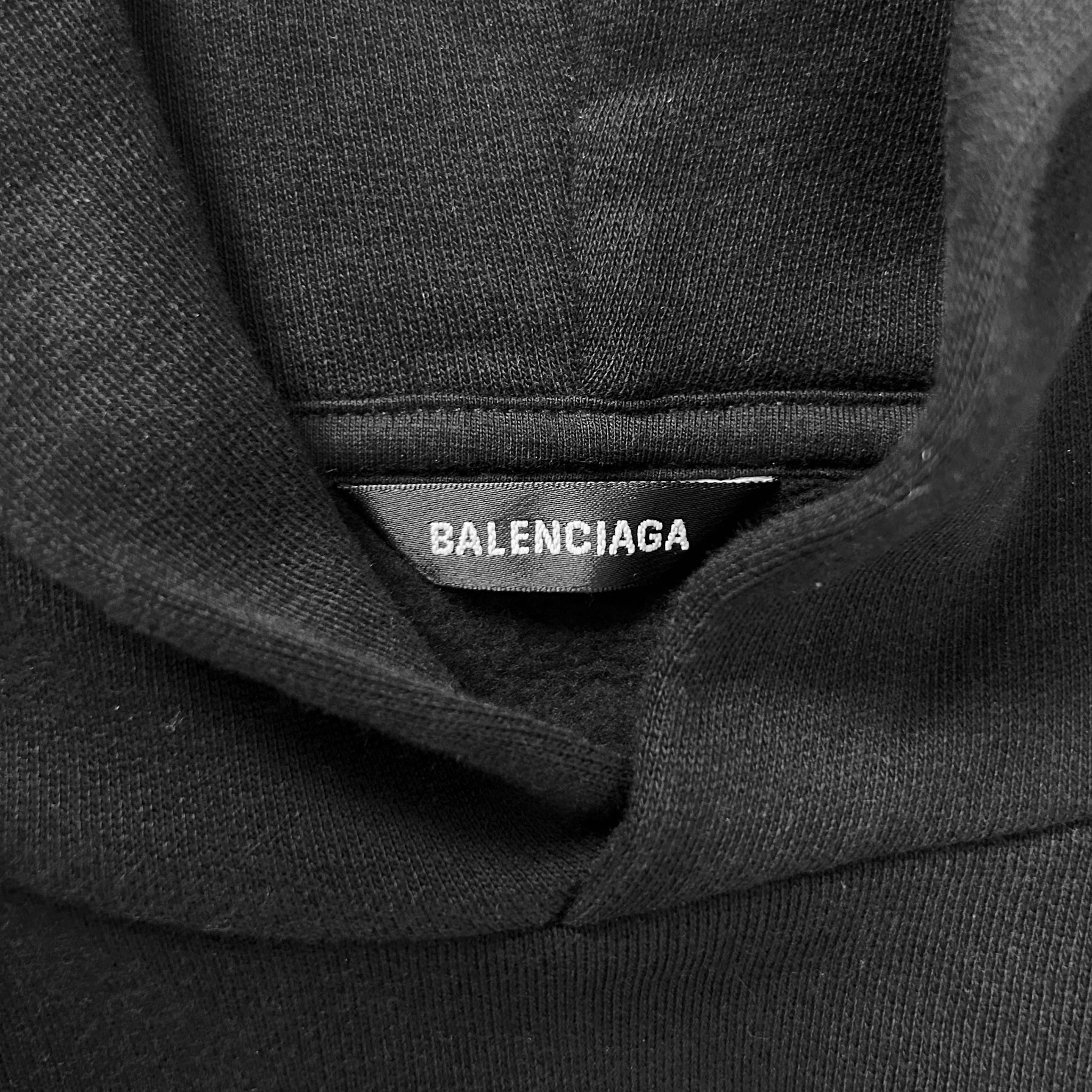 A close-up view of a black hoodie with a label that reads "BALENCIAGA".