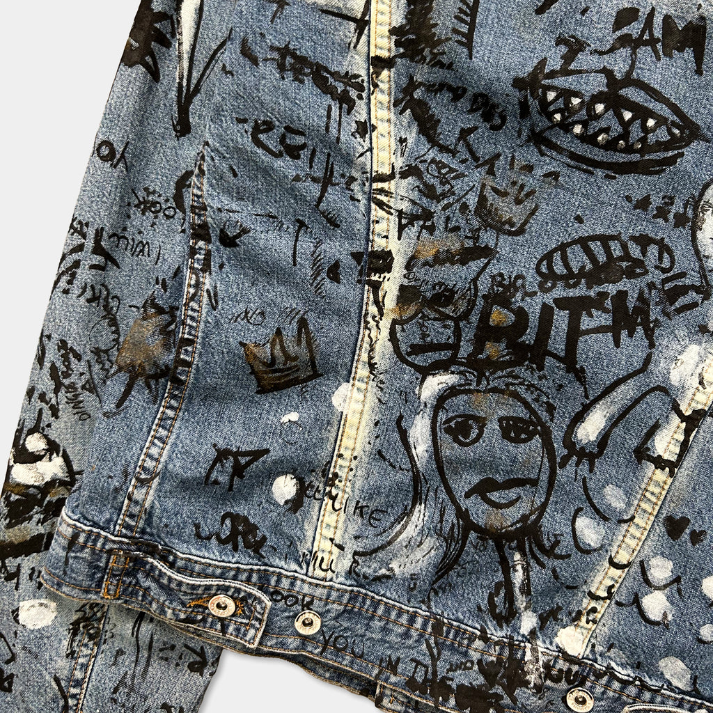 a close-up view of a denim jacket with various graffiti and doodles covering its surface.