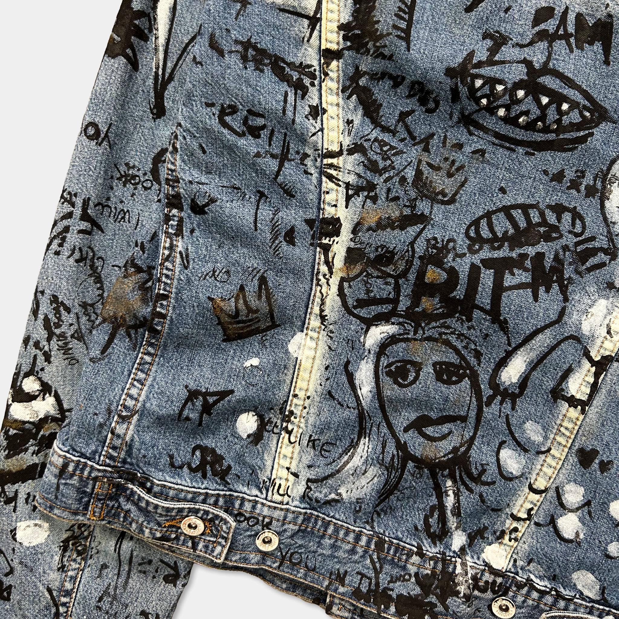 a close-up view of a denim jacket with various graffiti and doodles covering its surface.