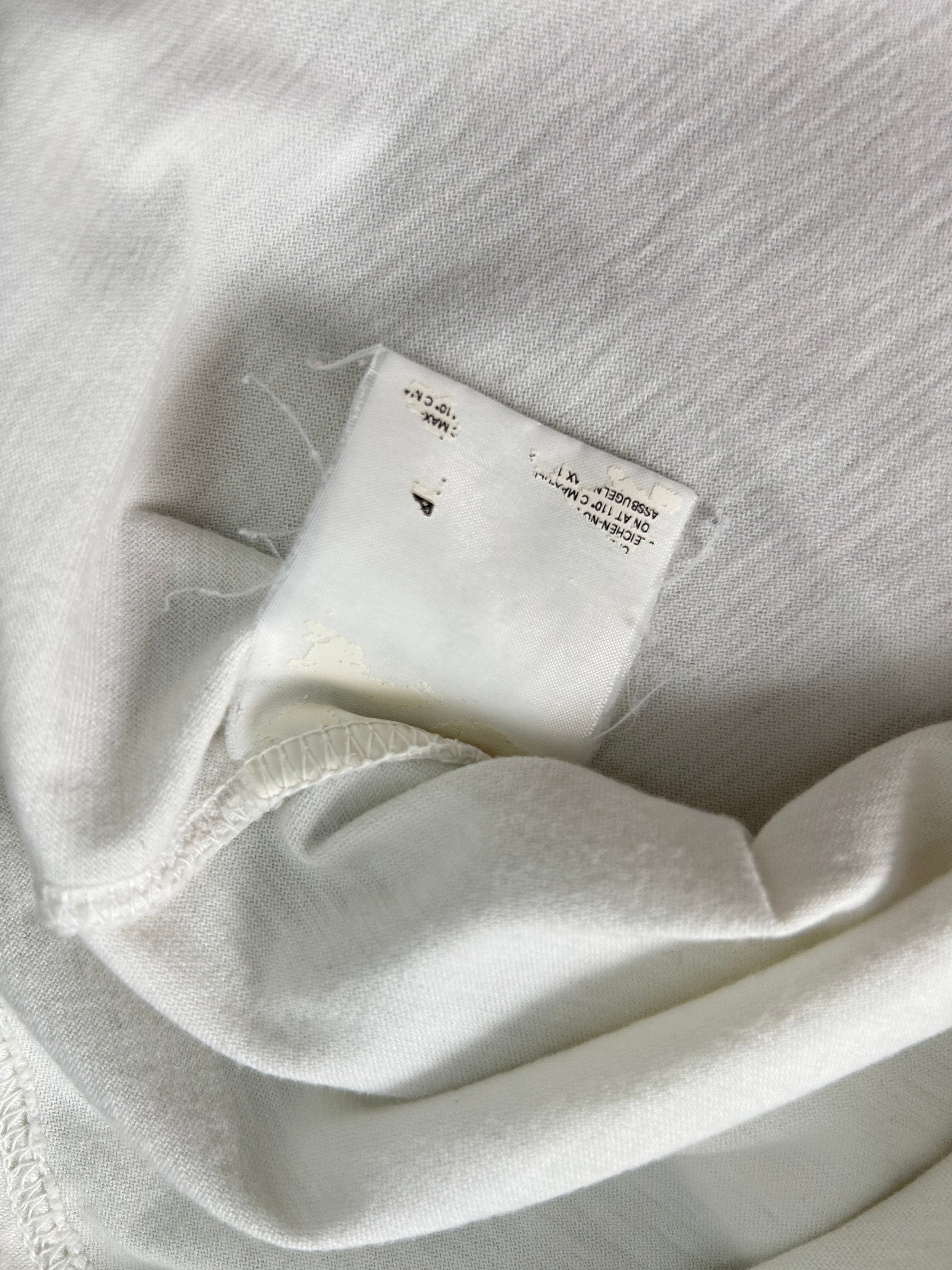 a close-up view of a white fabric, possibly a piece of clothing, with a small, torn label attached to it.
